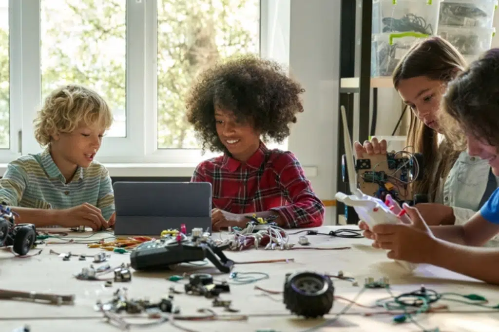 A diverse group of middle school students make robotic cars, using a tablet computer